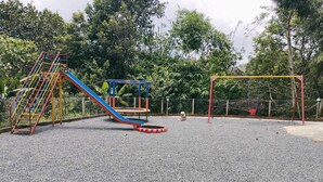 Un parque infantil con tobogán, estructuras de escalada y columpios.