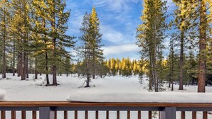 A snowy forest with a wooden deck in the foreground. - 1801 Jicarilla Drive 4 Bedroom Home by RedAwning (South Lake Tahoe)