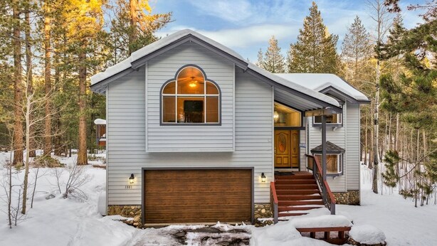 A two-story house with a wooden garage door, a large arched window, and a staircase leading to the entrance. - 1801 Jicarilla Drive 4 Bedroom Home by RedAwning (South Lake Tahoe)