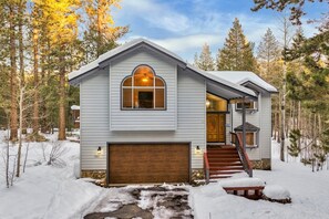A two-story house with a wooden garage door, a large arched window, and a staircase leading to the entrance. - 1801 Jicarilla Drive 4 Bedroom Home by RedAwning (South Lake Tahoe)