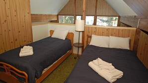 A small, cozy room with two single beds, wooden walls, a window, and a floor lamp. - 1116 Golden Bear 3 Bedroom Cabin by RedAwning (South Lake Tahoe)