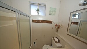 A small bathroom with a toilet, sink, and shower. There is a small window with a plant, and a mirror above the sink. - 1116 Golden Bear 3 Bedroom Cabin by RedAwning (South Lake Tahoe)