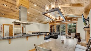 A spacious kitchen with a granite countertop, a stainless steel range hood, and a large dining table with chairs. - 2566 Del Norte 5 Bedroom Home by RedAwning (South Lake Tahoe)