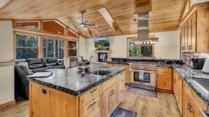 A spacious kitchen with wooden cabinets, a granite countertop, and a large island. - 2566 Del Norte 5 Bedroom Home by RedAwning (South Lake Tahoe)