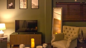 A living room with a television, a sofa, a coffee table with a candle, and framed pictures on the wall. - It' ta de JPN - Self Check-In Only (Osaka)