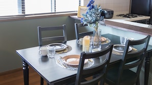 A dining table set for four with a vase of flowers, a candle, and a toaster. - It' ta de JPN - Self Check-In Only (Osaka)