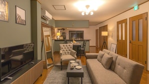 A living room with a TV, sofa, coffee table, and dining area with chairs and a table. - It' ta de JPN - Self Check-In Only (Osaka)