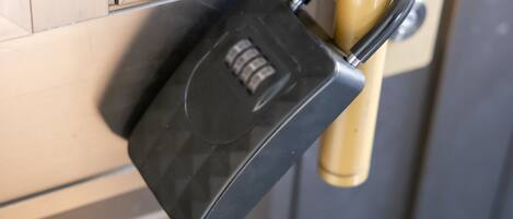 A close-up of a black electronic lock on a beige door handle.
