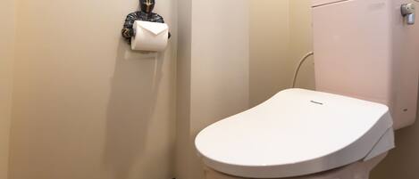 A white toilet with a tank, a toilet paper holder on the wall, and a brown baseboard.