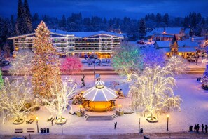 Ein verschneiter Platz mit beleuchteten Bäumen und einem zentralen Gazebo.