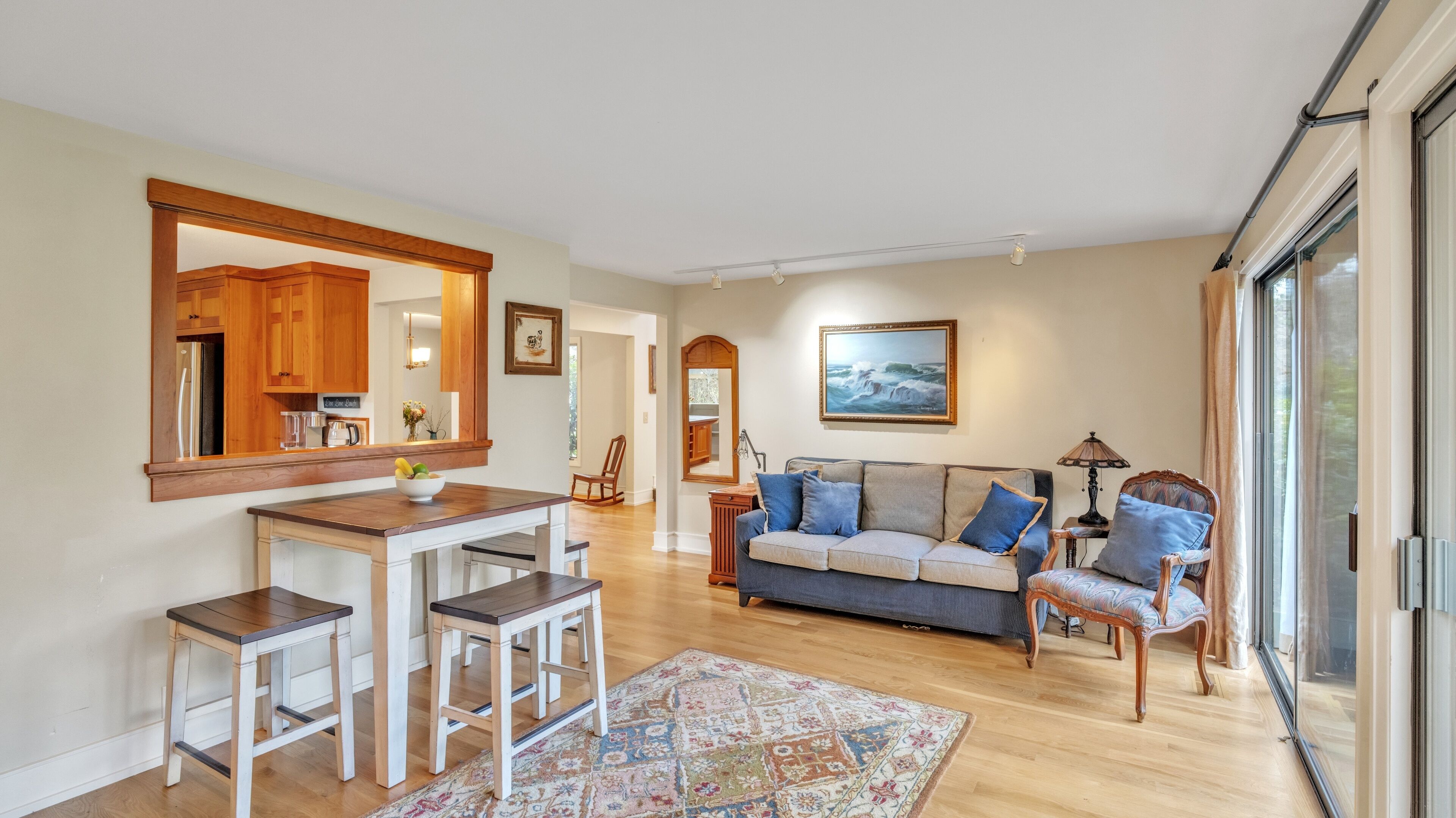 Ein geräumiges Wohnzimmer mit einer großen Couch, einer Essecke mit Holztisch und -bänken sowie einer Küche mit Holzschränken.