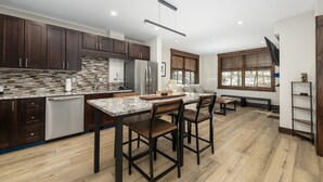 A modern kitchen with dark wooden cabinets, a granite countertop, and a built-in dishwasher.