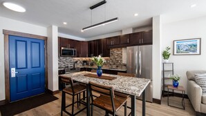 A modern kitchen with dark wood cabinets, a blue door, and a marble countertop.
