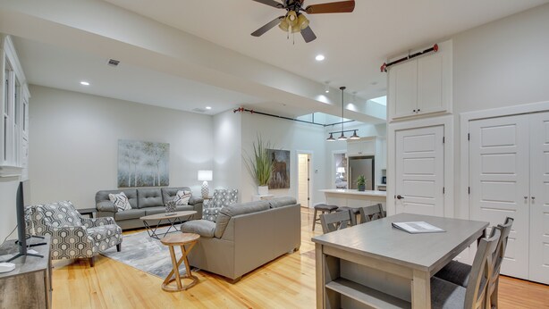 A modern living room with a grey sofa, patterned armchairs, a dining table, and a ceiling fan. - Spacious Downtown Hot Springs Vacation Rental! (Hot Springs)