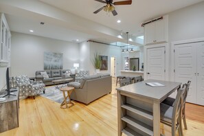 A modern living room with a grey sofa, patterned armchairs, a dining table, and a ceiling fan. - Spacious Downtown Hot Springs Vacation Rental! (Hot Springs)
