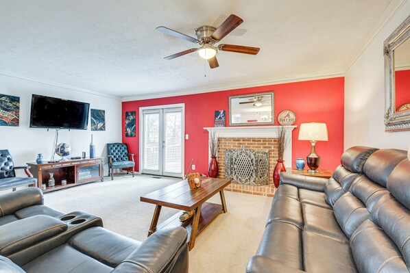 A living room with a fireplace, leather sofas, a wooden coffee table, and a ceiling fan.