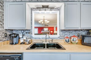A kitchen with a double sink, a coffee maker, a toaster, and a microwave.