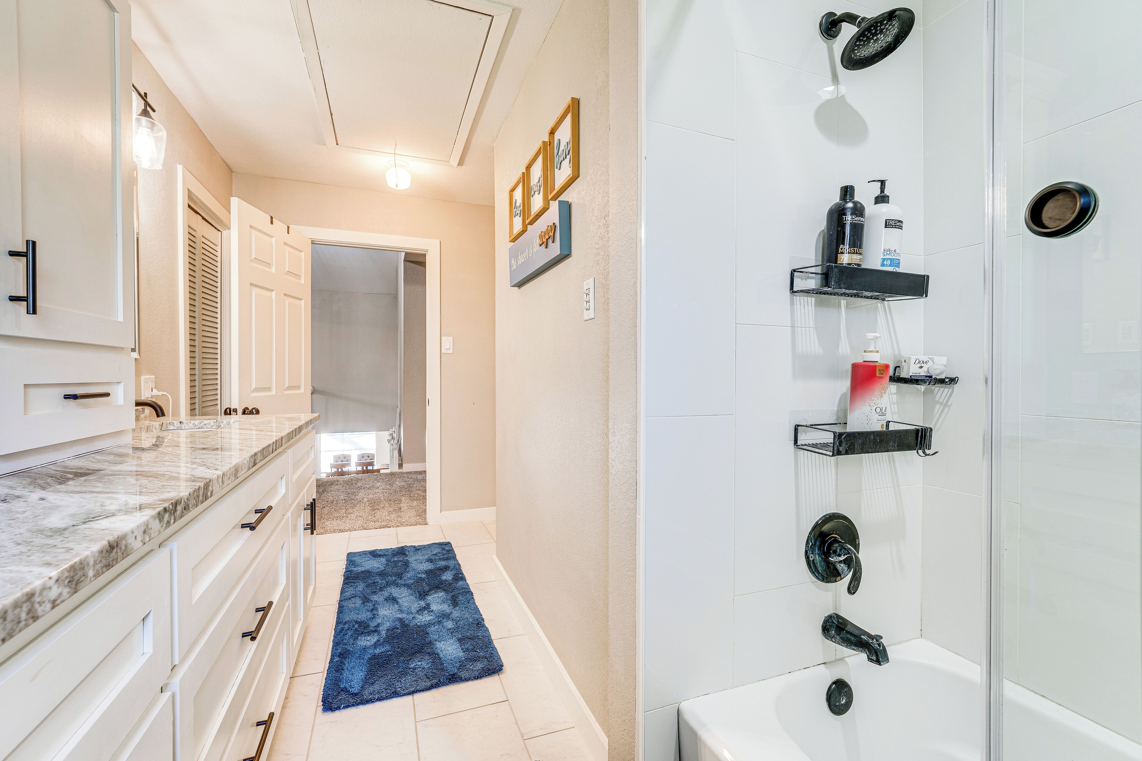 A modern bathroom with a shower, vanity, and a blue rug.