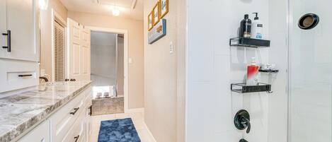 A modern bathroom with a shower, vanity, and a blue rug.