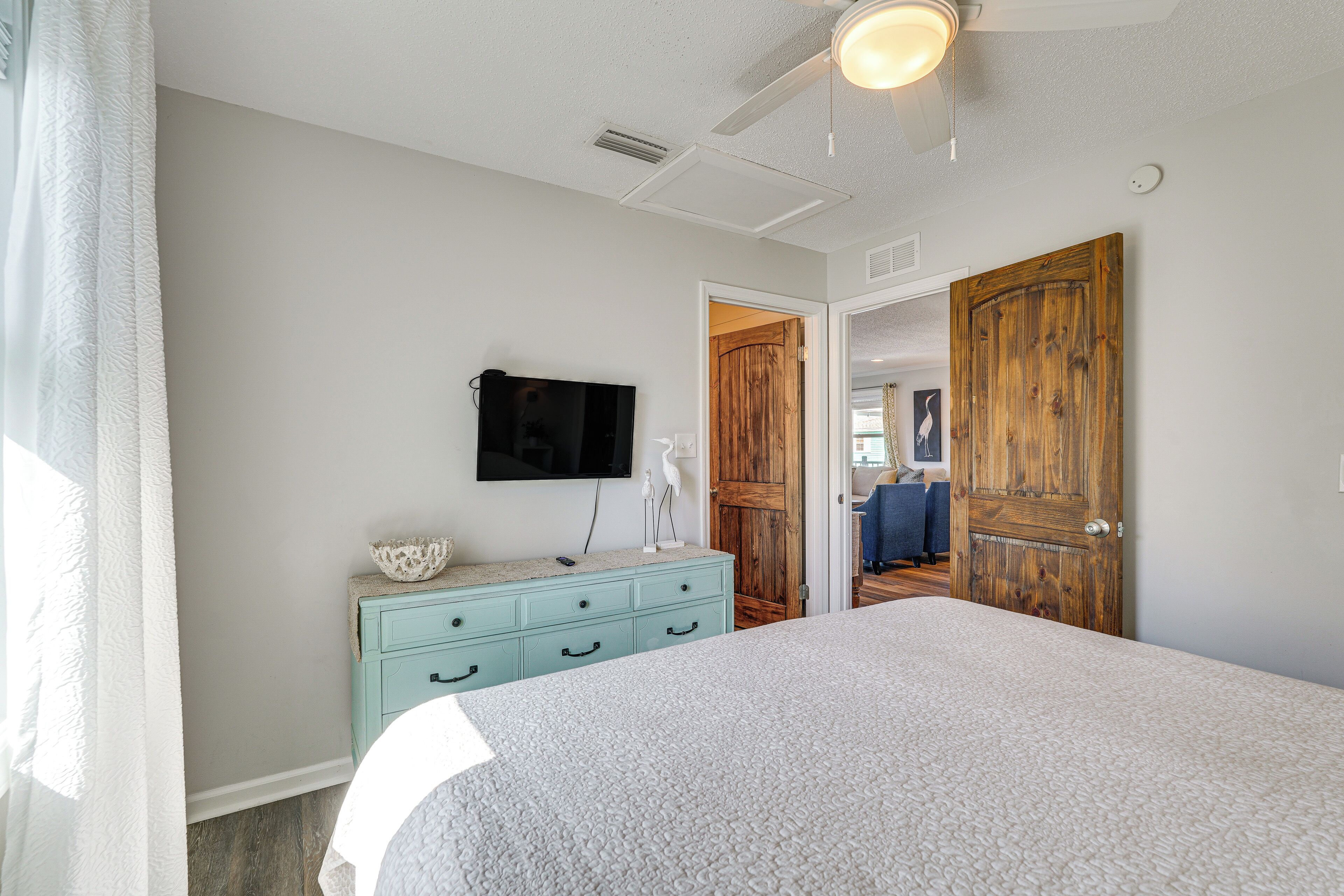 A bedroom with a bed, a dresser, a television, and a wooden door.