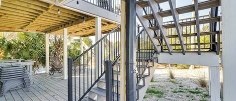 Una terrassa de fusta amb una escala que condueix a una zona coberta amb baranes.