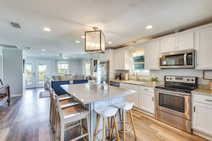 A modern kitchen with a central island, stainless steel appliances, and a view to the living area. - Cape San Blas Home w/ Pool Access: Walk to Beach! (Port St. Joe)