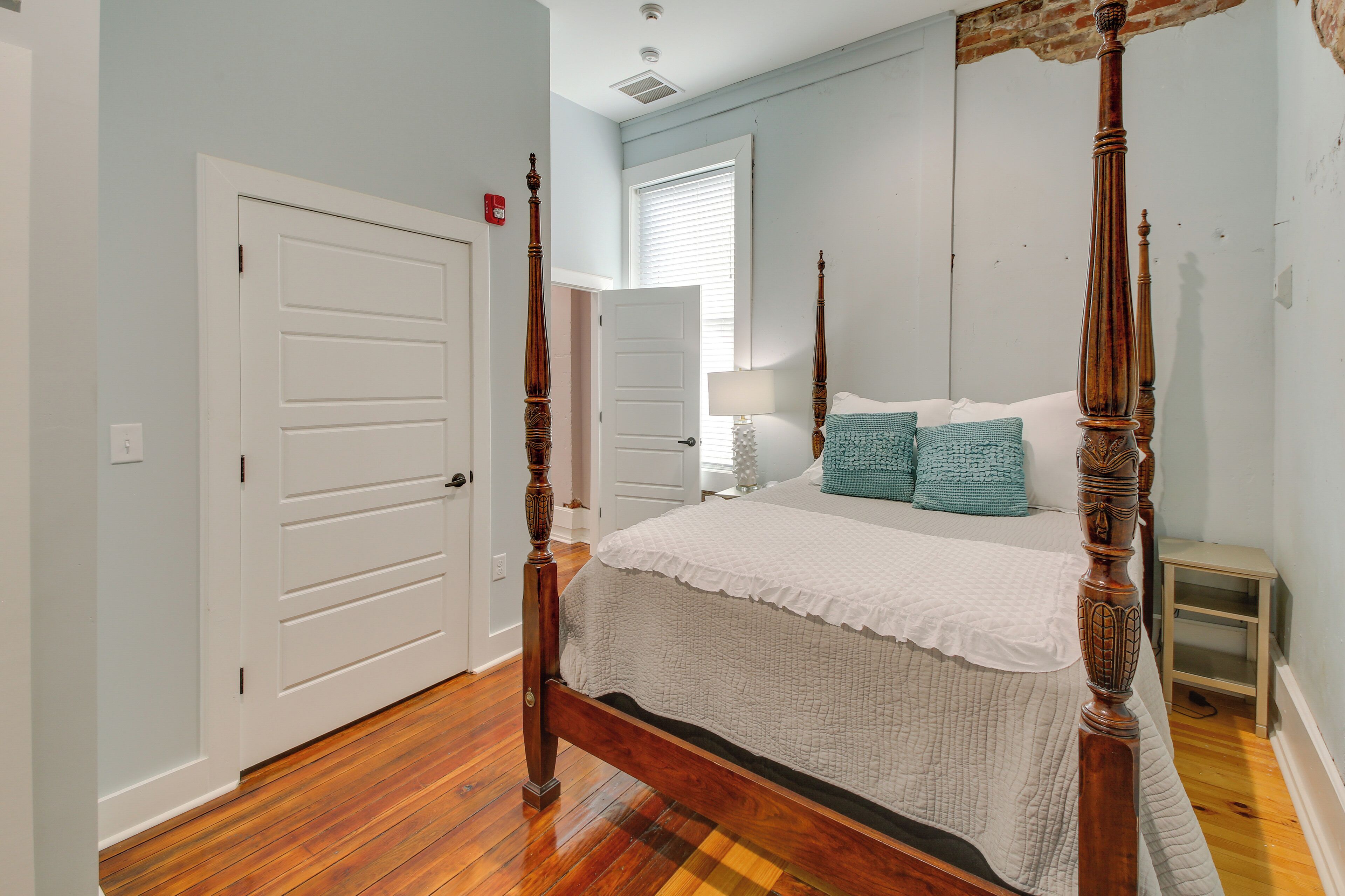 Un dormitorio con cama con dosel, una puerta blanca y suelo de madera.