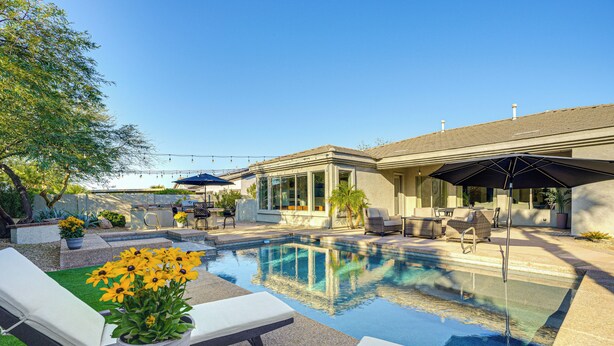 Ein Schwimmbecken mit Liegestühlen und einer Terrasse mit Gartenmöbeln.