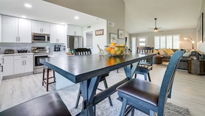 A spacious kitchen with modern appliances, a large island with bar stools, and a dining area with a sofa and coffee table. - Bright Tempe Home w/ Fenced Backyard! (Tempe)