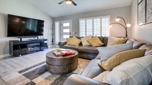 A modern living room with a flat-screen TV, leather sofa, and a round coffee table. - Bright Tempe Home w/ Fenced Backyard! (Tempe)