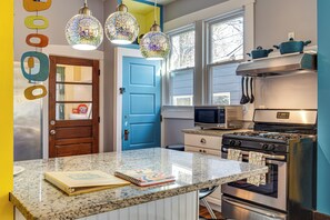 A kitchen with a blue door, stainless steel appliances, and a granite countertop. - Retro-inspired Indy Home: Walk to Fountain Square! (Indianapolis)