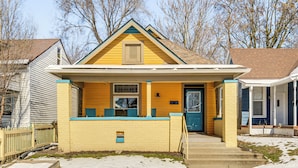 Une maison à deux étages avec une façade jaune et une porte bleue.