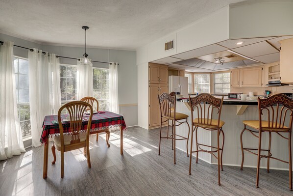 A dining area with a table set for four, wooden chairs, and a window with curtains. - Peaceful Mcalpin Home on 5 Acres w/ Private Deck! (Live Oak)