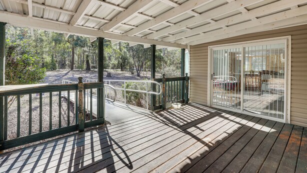 A covered outdoor area with a wooden deck, a glass door leading to a patio, and a view of a forested area. - Peaceful Mcalpin Home on 5 Acres w/ Private Deck! (Live Oak)