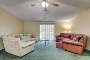 A living room with two sofas, a glass coffee table, a ceiling fan, and a window with blinds. - Peaceful Mcalpin Home on 5 Acres w/ Private Deck! (Live Oak)