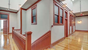 A spacious hallway with wooden floors and red-framed windows. - Downtown Hot Springs Condo Near Bathhouse Row! (Hot Springs)