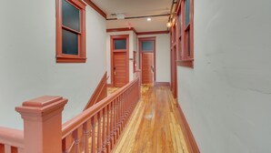 A hallway with wooden floors and red trim, leading to multiple doors. - Downtown Hot Springs Condo Near Bathhouse Row! (Hot Springs)