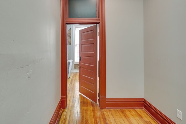 A hallway with wooden flooring and a red door leading to another room. - Downtown Hot Springs Condo Near Bathhouse Row! (Hot Springs)