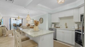 A modern kitchen with white cabinetry, a central island, and stainless steel appliances. - Beach Villas # 505 - Bogo24 2 Bedroom Condo by RedAwning (Fort Myers Beach)