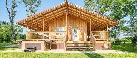 A wooden cabin with a porch, a deck, and a garage.