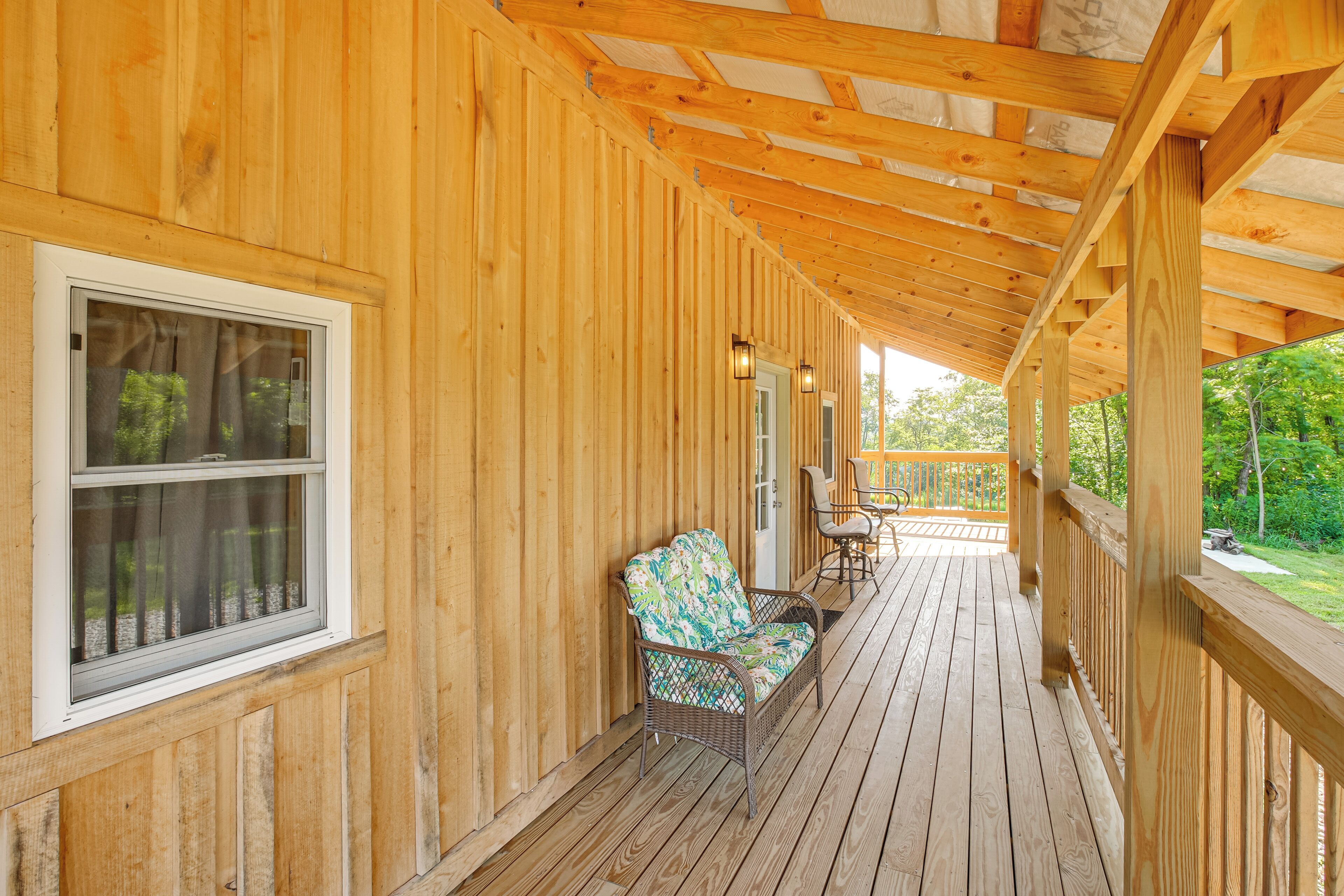 A wooden porch with a wicker chair and a table, a window, and a door.