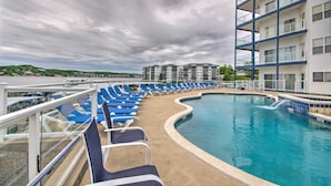 A pool area with blue lounge chairs and a clear blue pool. - Lake Ozark Condo w/ Water Views & Pool Access! (Lake Ozark)