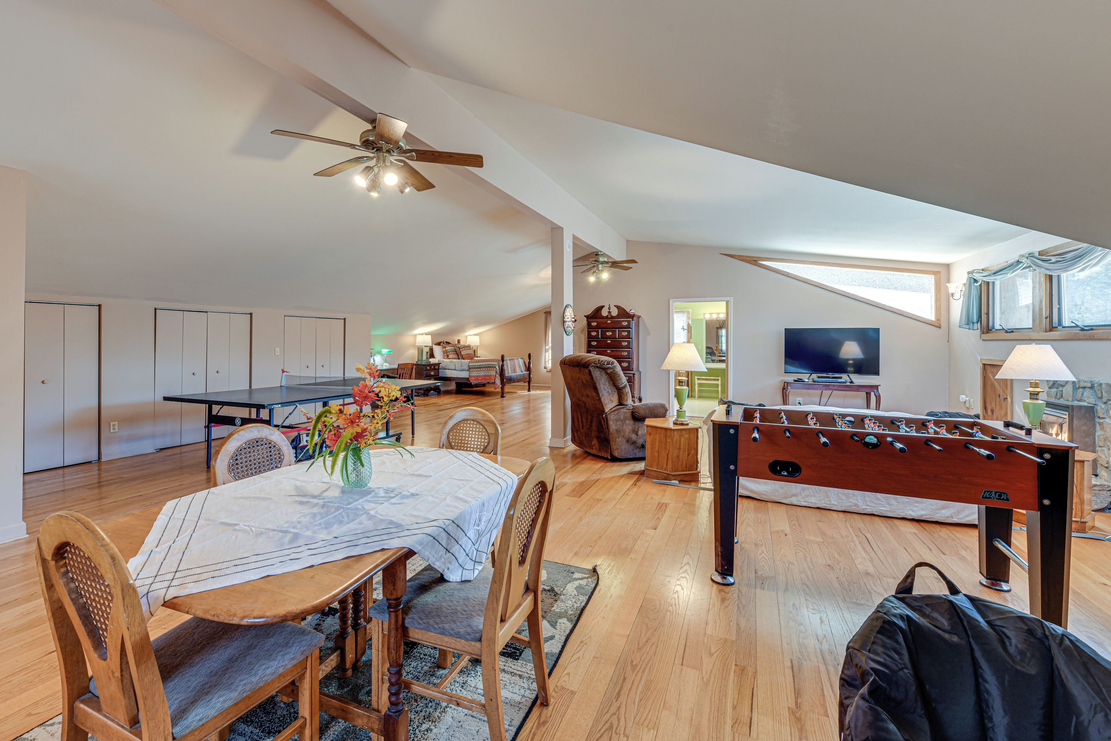 A spacious loft with a dining area, a foosball table, and a cozy seating area with a fireplace.