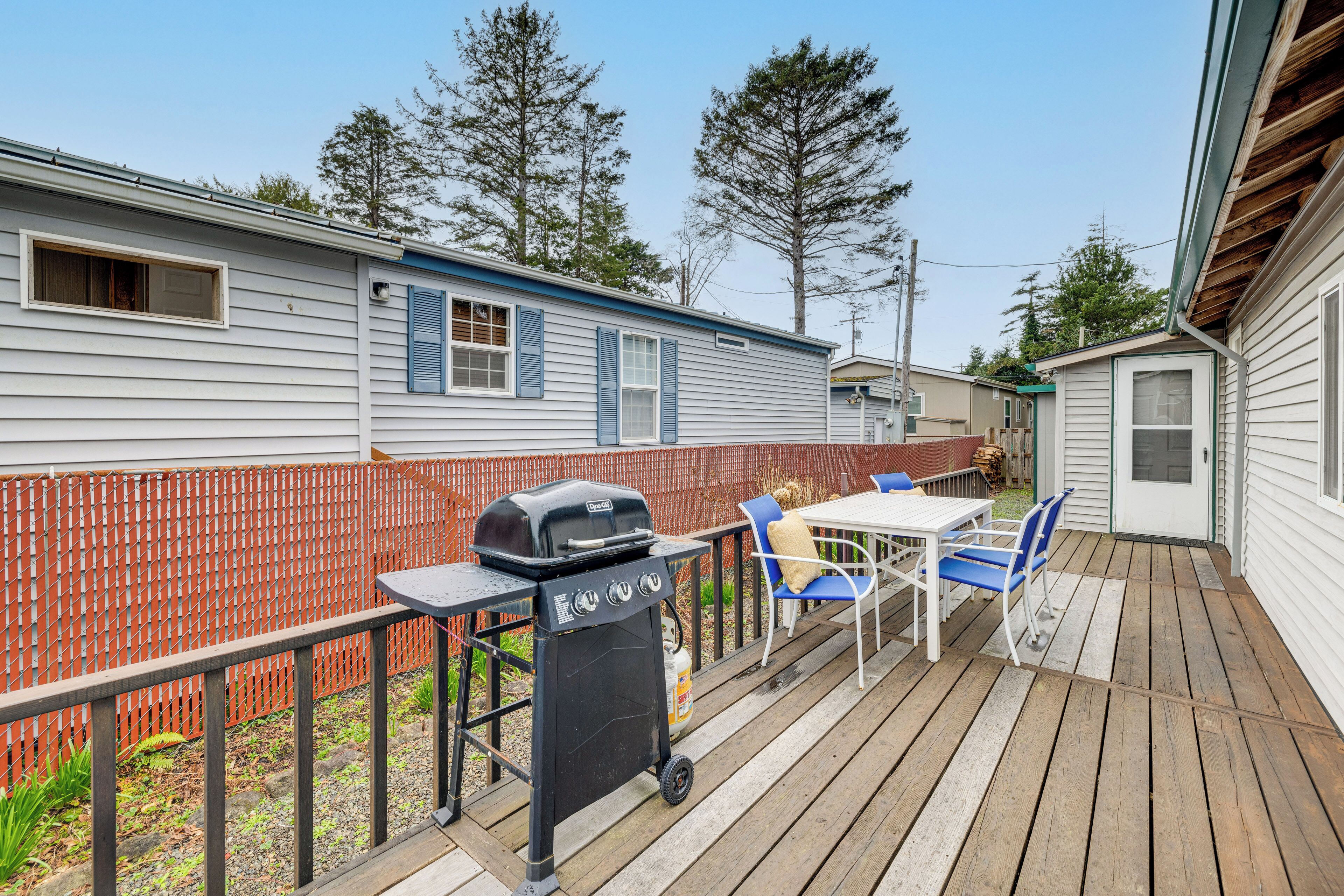 A wooden deck with a grill, chairs, and a table.