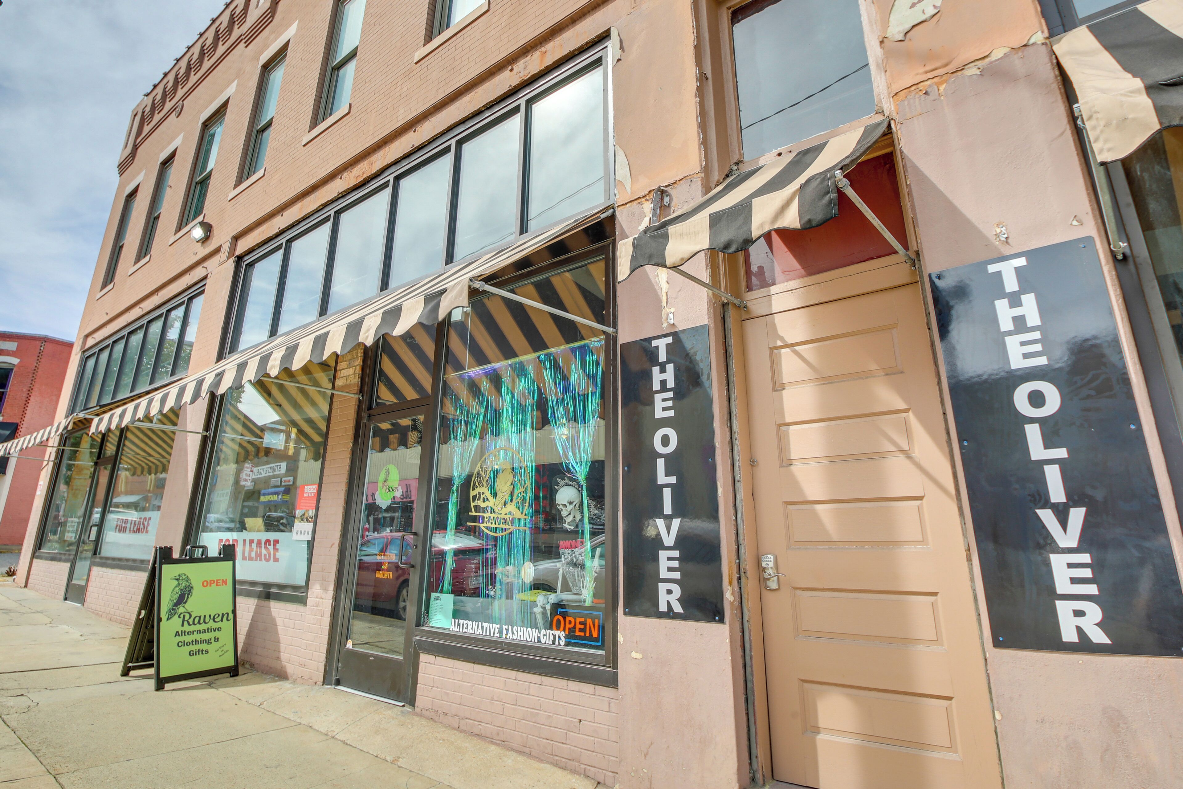 A storefront with a sign reading "THE OLIVER" and a window display featuring a mannequin.