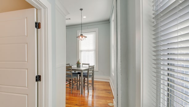 A hallway with a wooden floor, a dining area with a table and chairs, and a window with blinds. - Modern Downtown Hot Springs Vacation Rental! (Hot Springs)