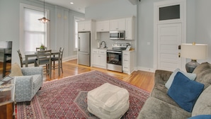 A modern living room with a sofa, ottoman, and a dining area with chairs and a table. - Modern Downtown Hot Springs Vacation Rental! (Hot Springs)