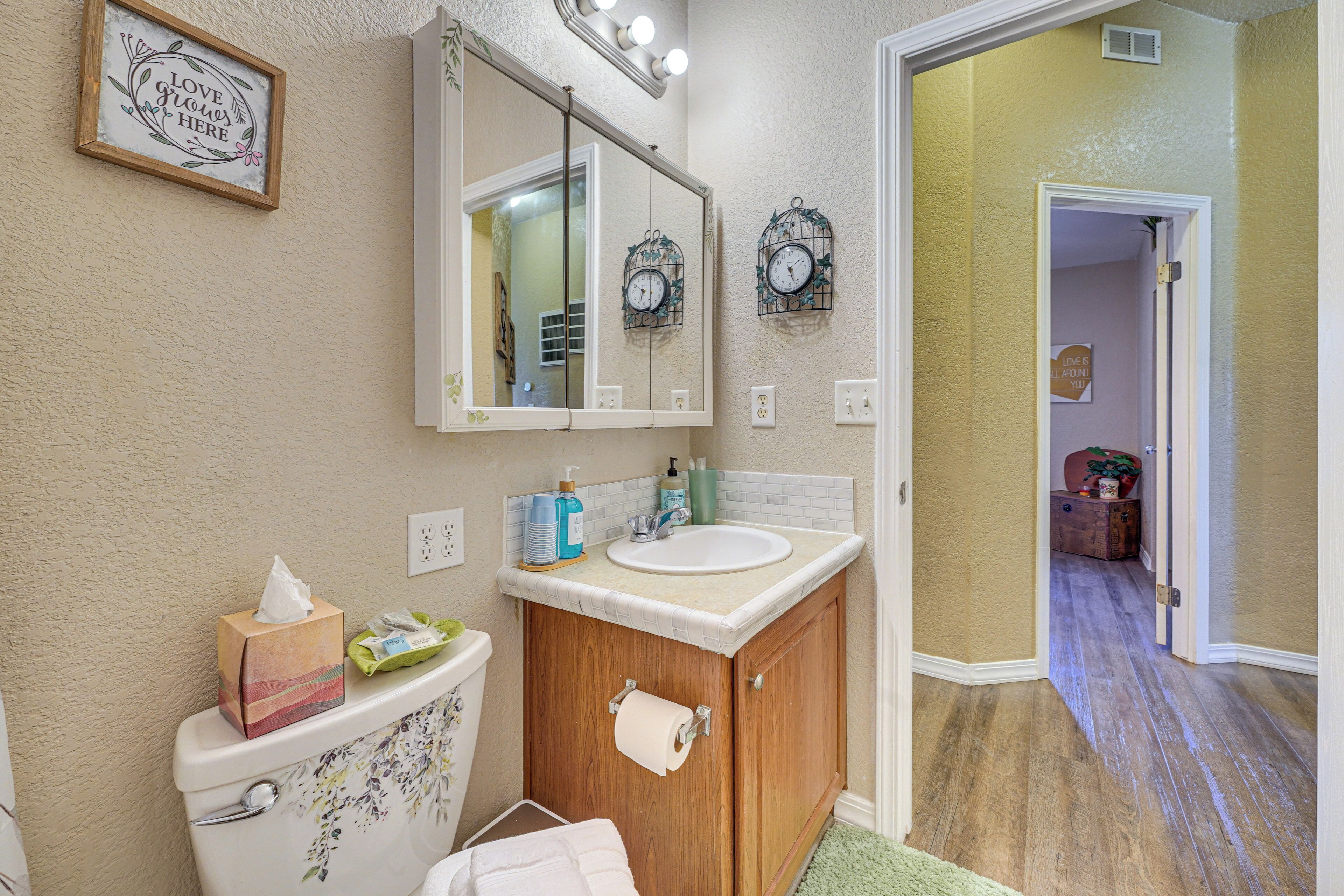 A bathroom with a toilet, sink, mirror, and wooden cabinet.