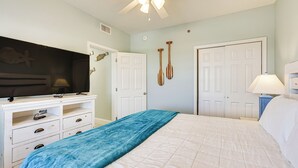 Ein Schlafzimmer mit einem Bett, einem Fernseher auf einer Kommode und zwei Türen.