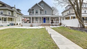 A two-story house with a front porch, a blue door, and a small front yard with a sidewalk. - Long Branch Getaway - Walk to Beaches & Dining! (Long Branch)